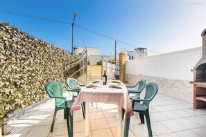 An outdoor patio with a table set for two, surrounded by green chairs, a stone wall, and a clear blue sky. - 2203 Villa Lucia - Bilo 1 by Barbarhouse (Nardò)