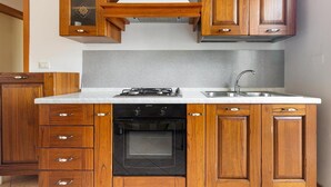 A kitchen with wooden cabinets, a white countertop, a stove, an oven, and a sink. - 2203 Villa Lucia - Bilo 1 by Barbarhouse (Nardò)