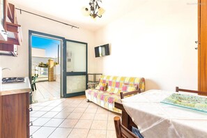 A room with a sofa, a dining table, a TV mounted on the wall, and a sliding glass door leading to an outdoor area. - 2203 Villa Lucia - Bilo 1 by Barbarhouse (Nardò)