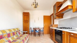 A compact kitchen with wooden cabinets, a dining table with chairs, and a sofa. - 2203 Villa Lucia - Bilo 1 by Barbarhouse (Nardò)