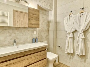 A modern bathroom with a wooden vanity, a toilet, and a shower area.