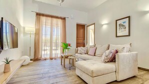 A modern living room with a sofa, a coffee table, and a TV. - Scenic Villa in Pigadakia With Private Pool (Zakynthos)