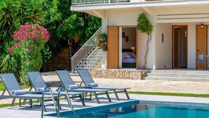 A modern poolside area with lounge chairs, a swimming pool, and a stone staircase leading to a bedroom. - Scenic Villa in Pigadakia With Private Pool (Zakynthos)