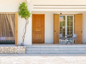 A wooden door with a nameplate, a stone wall, and a small tree.