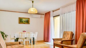 A living room with a dining area, wooden flooring, a chandelier, a painting, and curtains. - Holiday Home in Senj With Pool Near Beach (Senj)