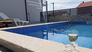 A swimming pool with a glass of white wine on the edge. - Holiday Home in Senj With Pool Near Beach (Senj)