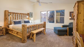 A rustic bedroom with a wooden bed, a bench, a chair, and a large window. - Great Location Near Parks | Pet-Friendly | Pool + Hot Tub Access (Moab)
