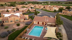 A residential area with multiple houses, a swimming pool, and a mountain backdrop. - Great Location Near Parks | Pet-Friendly | Pool + Hot Tub Access (Moab)