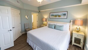 Una camera da letto con un letto grande, due comodini con lampade, un ventilatore a soffitto e una porta.