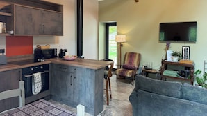 Een moderne keuken met een inbouw eiland, een zithoek met een bank, en een aan de muur bevestigde televisie.