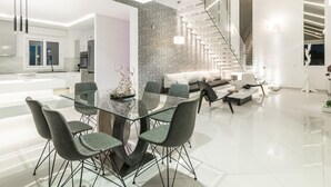 A modern kitchen with white cabinets, a glass dining table, and a staircase leading to an upper level.
