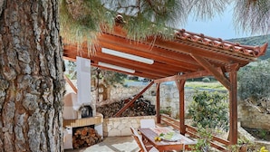 An outdoor patio with a stone fireplace, wooden pergola, and a table with chairs. - Fantastic Holiday Home in Karteros With Pool (Hersonissos)