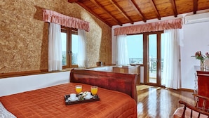 A hotel room with a wooden ceiling, a large bed with a red quilt, two bedside tables, a wooden chair, and a balcony with a view. - Fantastic Holiday Home in Karteros With Pool (Hersonissos)