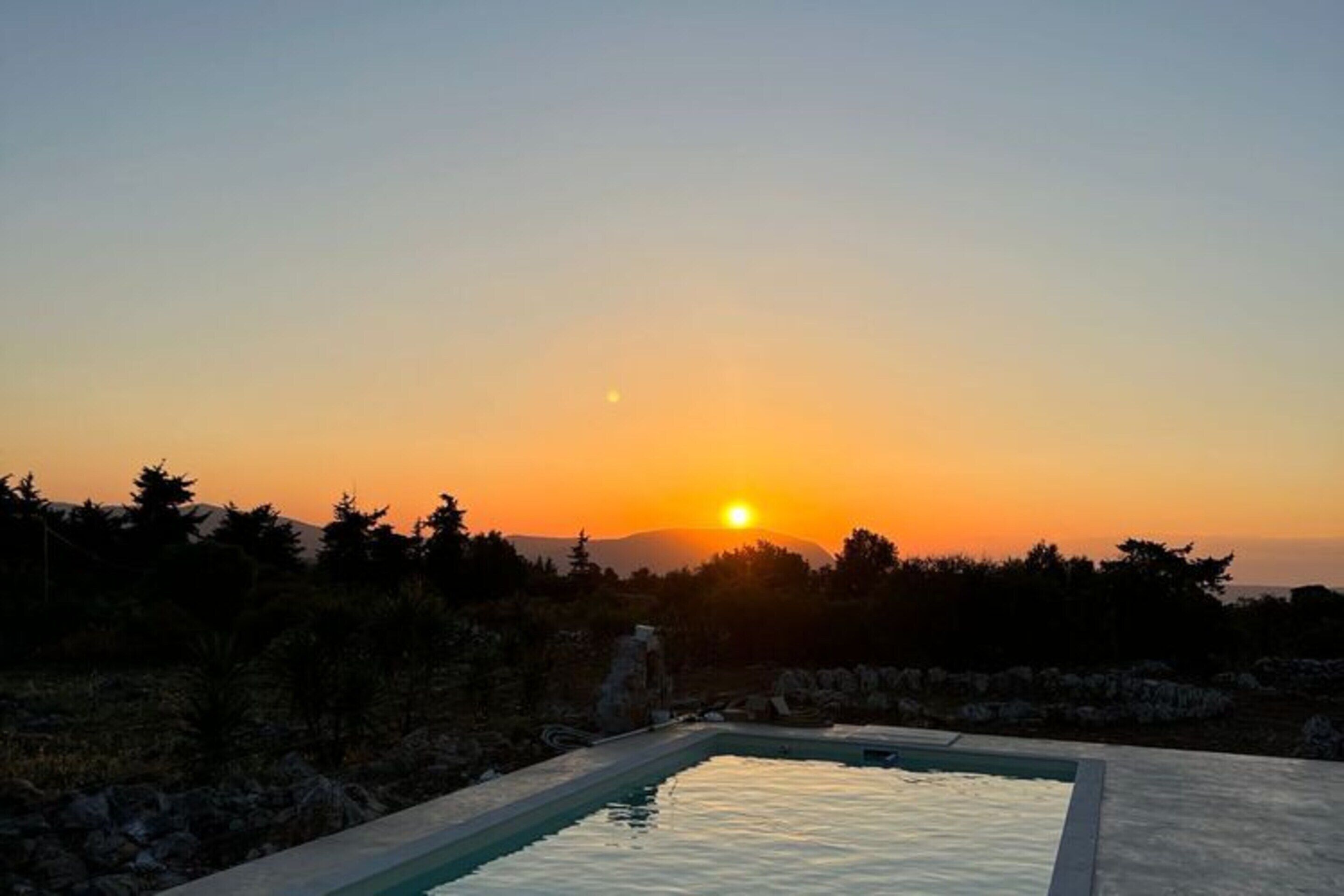 A swimming pool at sunset with a mountain backdrop.