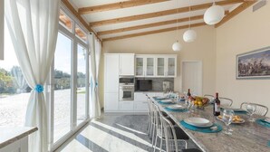 A modern kitchen with white cabinets, a marble countertop, and a dining area set for six. - 673 Villa con Piscina a Ruffano Gallipoli (Ruffano)