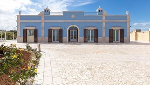 A building with a blue facade, multiple doors with shutters, and a tiled courtyard. - 673 Villa con Piscina a Ruffano Gallipoli (Ruffano)