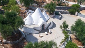 A white, dome-shaped building with a stone pathway leading to it, surrounded by trees and a stone wall. - 661 Villa con Piscina e Vista Panoramica a Ostuni (Ostuni)