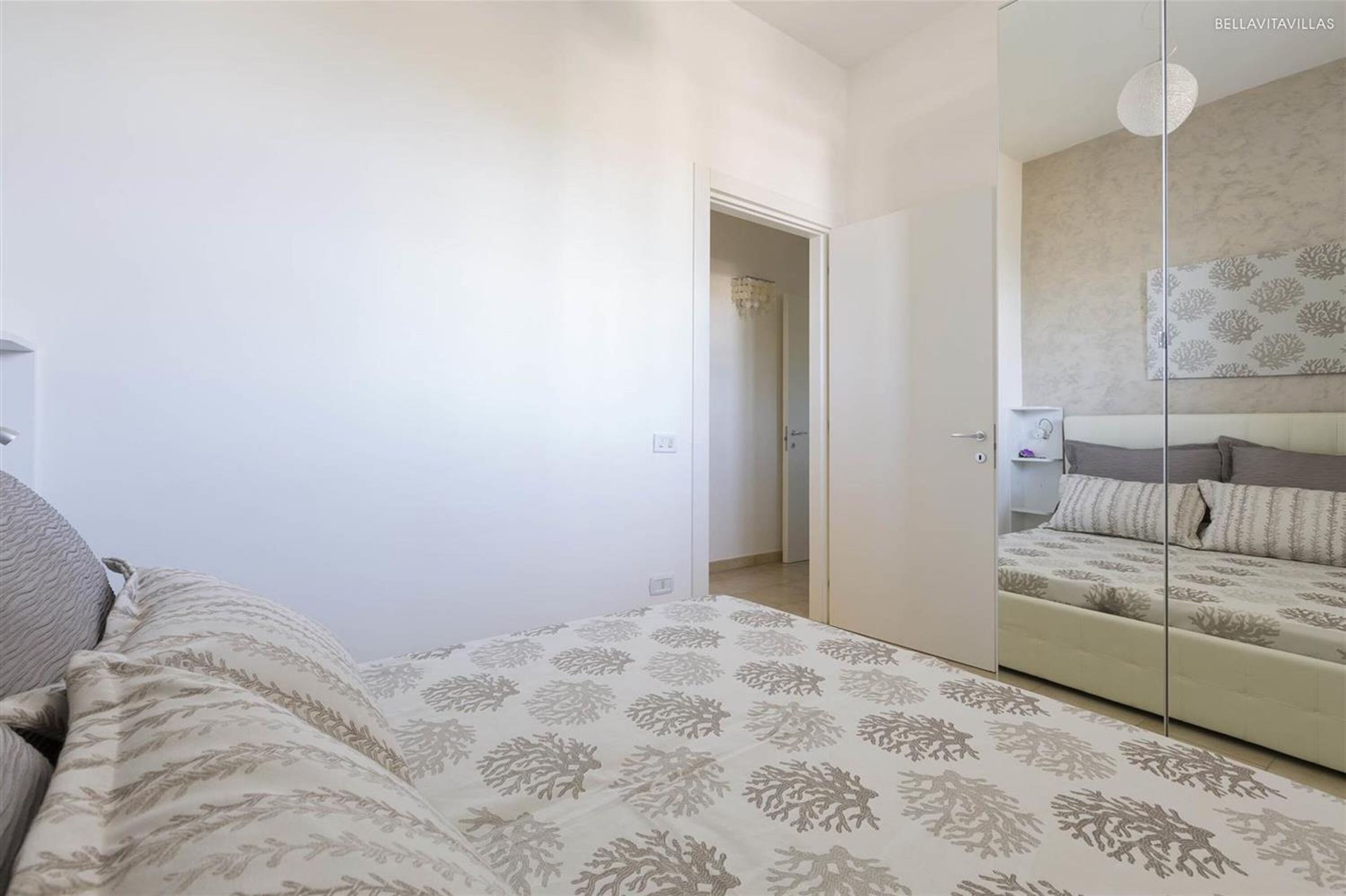 Quarto com cama, guarda-roupa e porta que dá para outro cômodo.