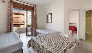 A bedroom with two single beds, a large window with a view of a balcony, and a door leading to another room. - 1297 Versomare - Bilocale Lu Sule (Porto Cesareo)
