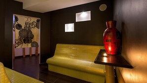 A room with a yellow tiled bench, a red vase on a small table, and a wall with a decorative panel and two illuminated panels. - 1742 Silver Hotel - Le Triple (Matino)