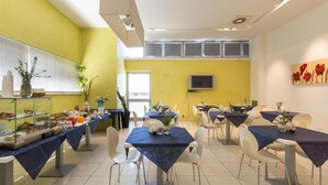 A dining area with tables and chairs, a buffet with food and drinks, and a television on the wall. - 1742 Silver Hotel - Le Triple (Matino)
