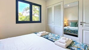 Ein Schlafzimmer mit zwei Betten, einem Fenster, einem Spiegel und einer Tür.