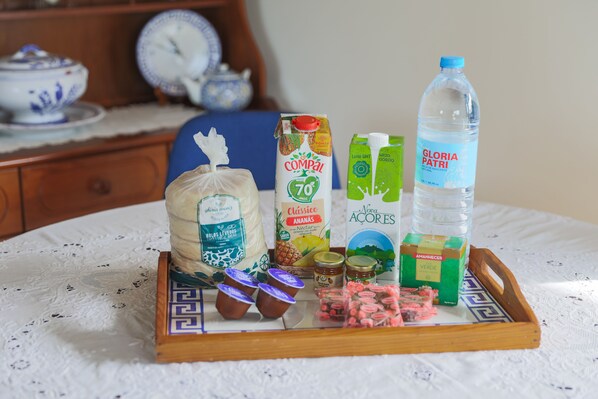 A tray with various food items and a bottle of water on a table. - O Nosso Refúgio (Água de Pau)