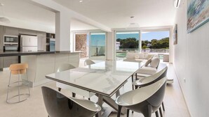 A modern kitchen with a dining area, large windows, and a view of the outdoors. - 1934 Villa Punta Ristola (Castrignano del Capo)