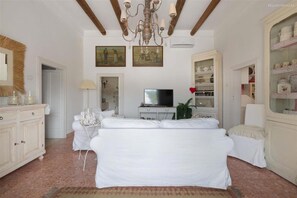 Experience a classic hotel room with a large bed, television, and elegant chandelier.