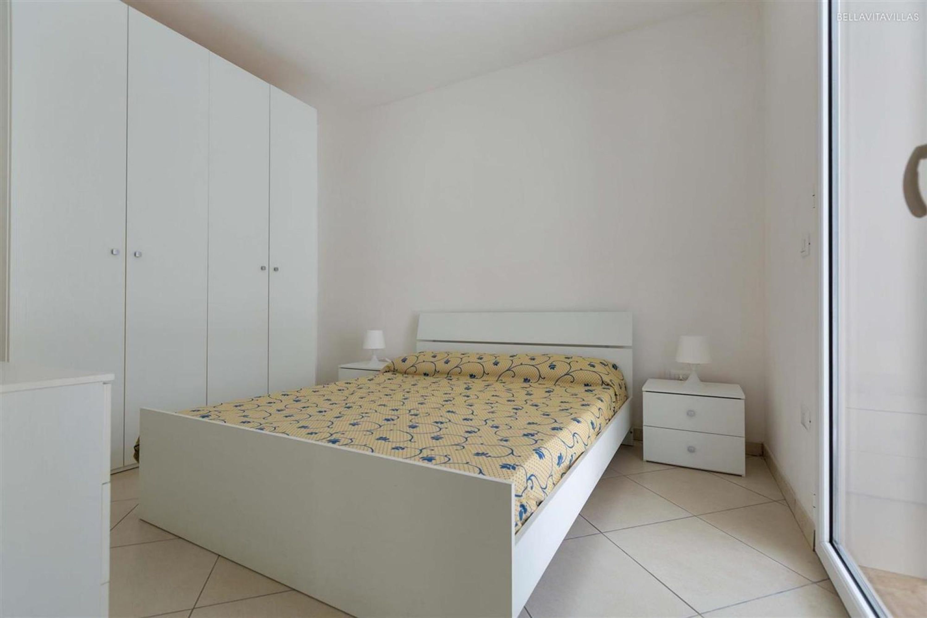 Un dormitorio con cama, mesitas de noche y un armario.