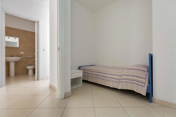 A small, clean room with a bed, a desk, and a bathroom with a sink and toilet. - 2371 Villette Girovagando - Trilo Superior by Barbarhouse (Melendugno)