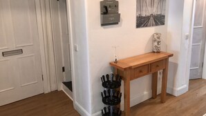 A hallway with a wooden console table, a wall-mounted clock, and a framed picture. - Stunning 3-bed Apartment in Edinburgh (Edinburgh)