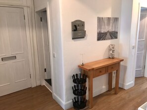 A hallway with a wooden console table, a coat rack, and a framed picture on the wall.