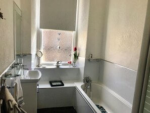 A bathroom with a window, a sink, a mirror, a bathtub, and a towel rack. - Stunning 3-bed Apartment in Edinburgh (Edinburgh)