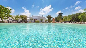 Une piscine aux eaux cristallines, avec des chaises longues et un bâtiment blanc en arrière-plan.