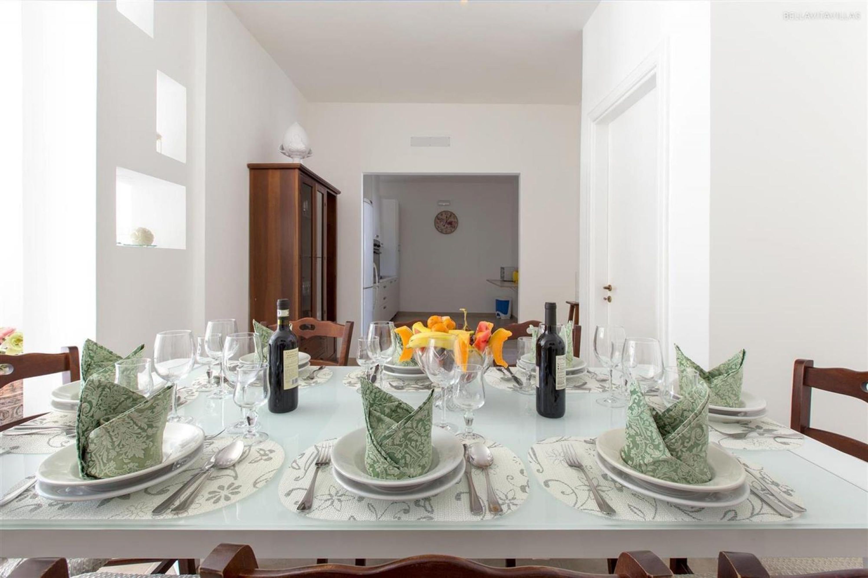 Una mesa de comedor lista para una comida, con platos, vasos y cubiertos.