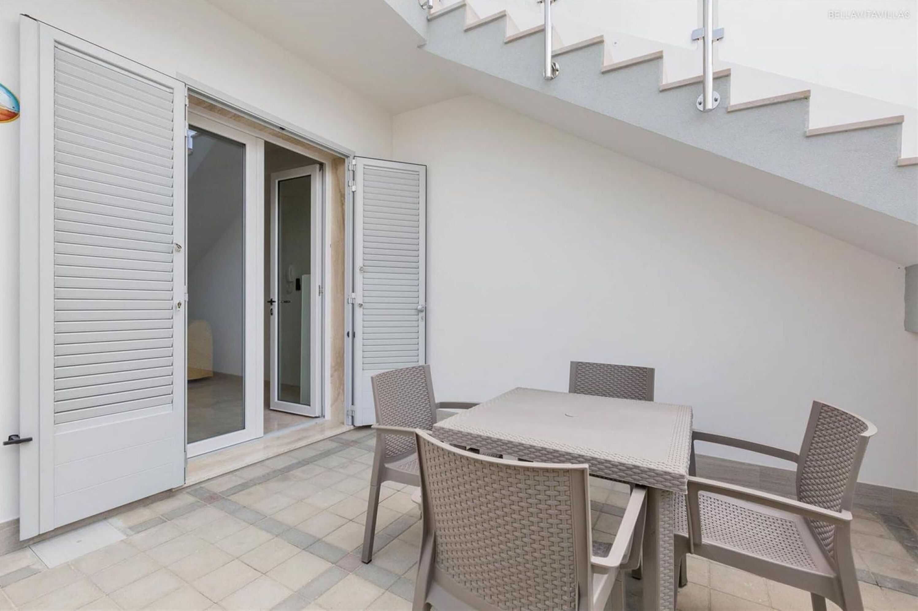 A dining area with a table and chairs, a sliding glass door, and a staircase.