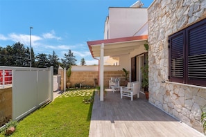 Een modern huis met een stenen gevel, een overdekt terras met tuinmeubilair en een verzorgd gazon.