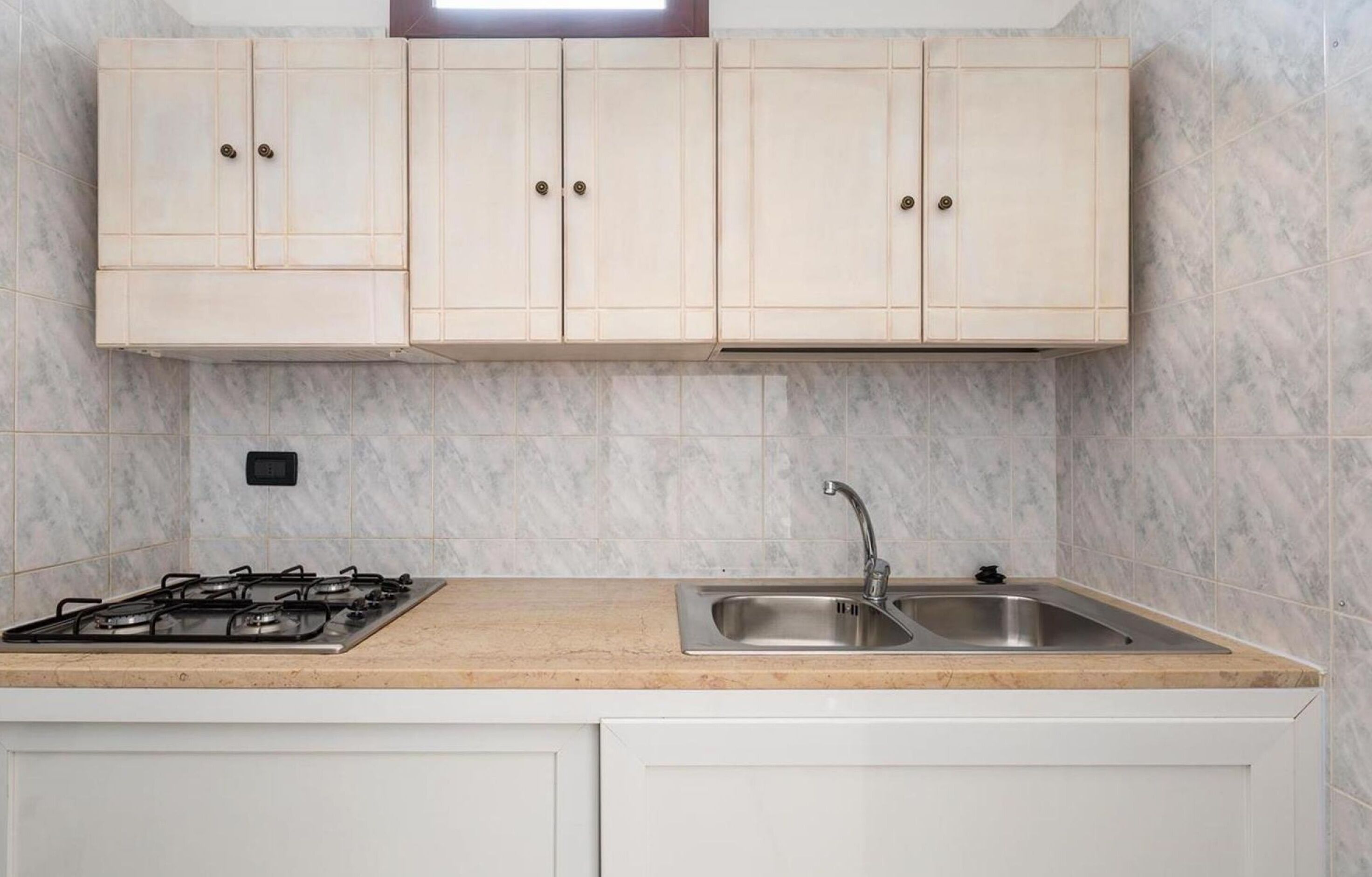 A kitchen with a gas stove, a sink, and light-colored cabinets.