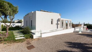 Un edificio moderno blanco con techo plano, un pequeño porche y un camino de entrada de grava.