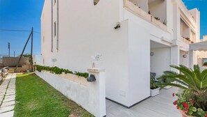 A modern white building with a flat roof, a balcony with potted plants, and a well-maintained lawn. - 2133 Maresidence - Camere Matrimoniali (Salve)