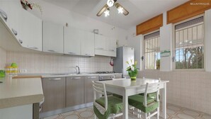 A modern kitchen with white cabinets, a dining table with chairs, and a patterned floor. - 2338 Bilo Imma B by Barbarhouse (Porto Cesareo)