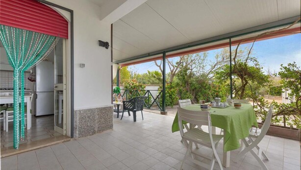 A covered patio with a table and chairs, a dining area with a white table and chairs, and a view of greenery and trees. - 2338 Bilo Imma B by Barbarhouse (Porto Cesareo)
