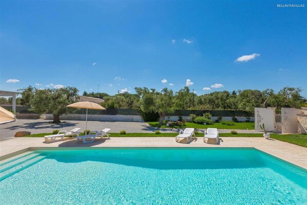 Une piscine avec des chaises longues et une pergola.