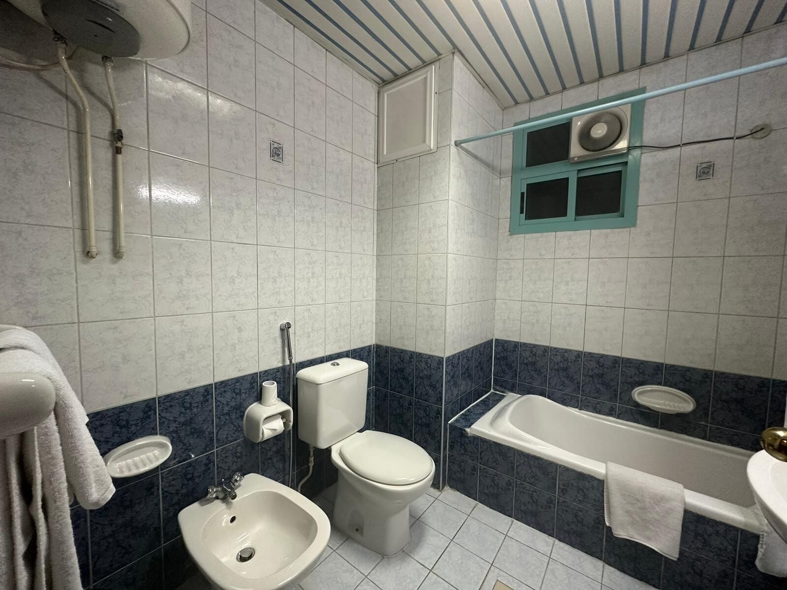Une salle de bain équipée d’une baignoire, de toilettes, d’un bidet et d’un lavabo.