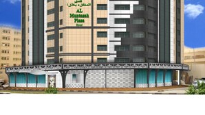 En moderne hotelbygning med et tydeligt skilt, der viser "AL Muntashah Plaza Hotel".