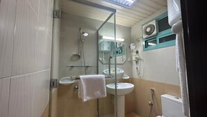 Et badeværelse med bruseniche i glas, to håndvaske, et toilet og et spejl.