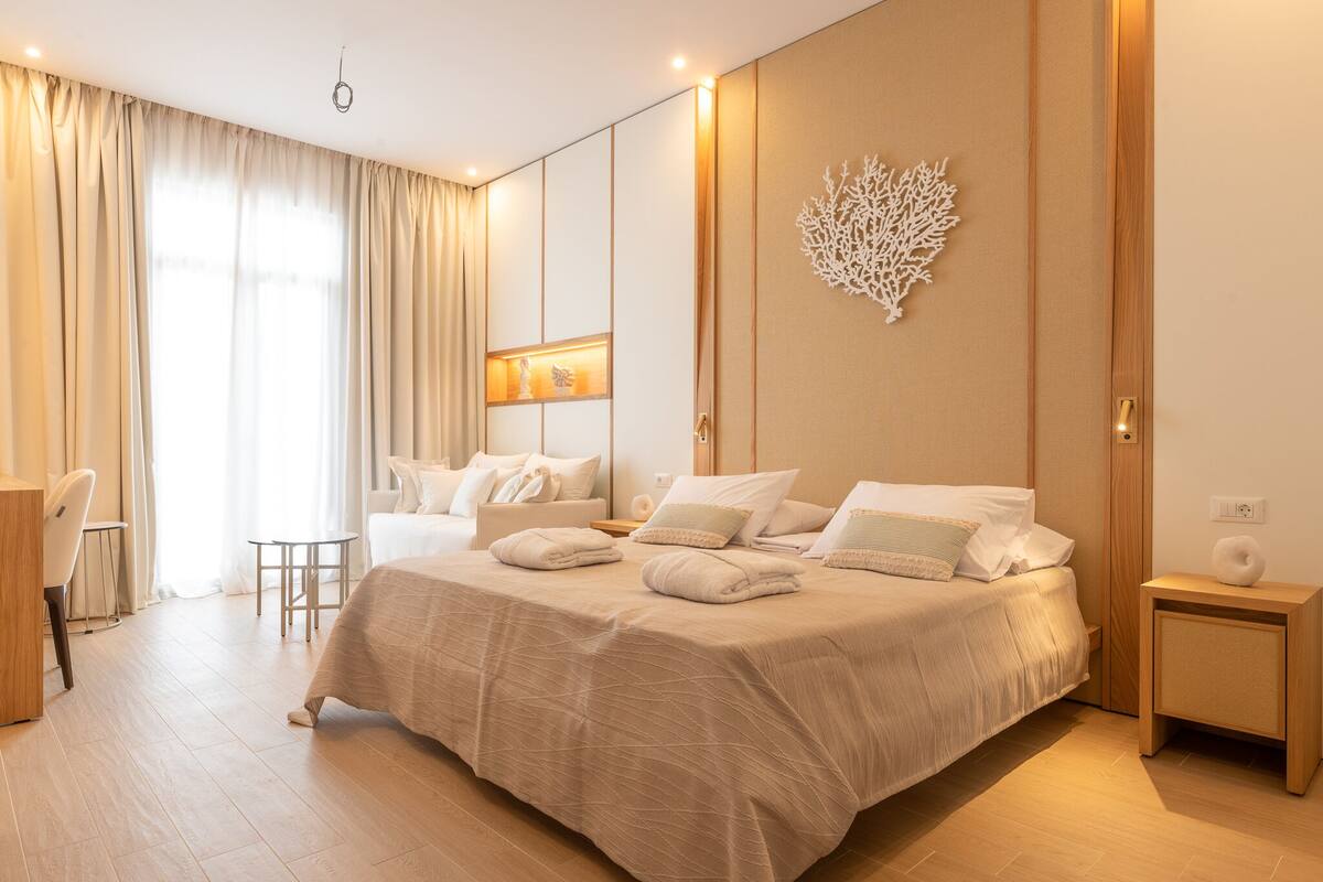 A modern hotel room with a large bed, a desk, and a chair.