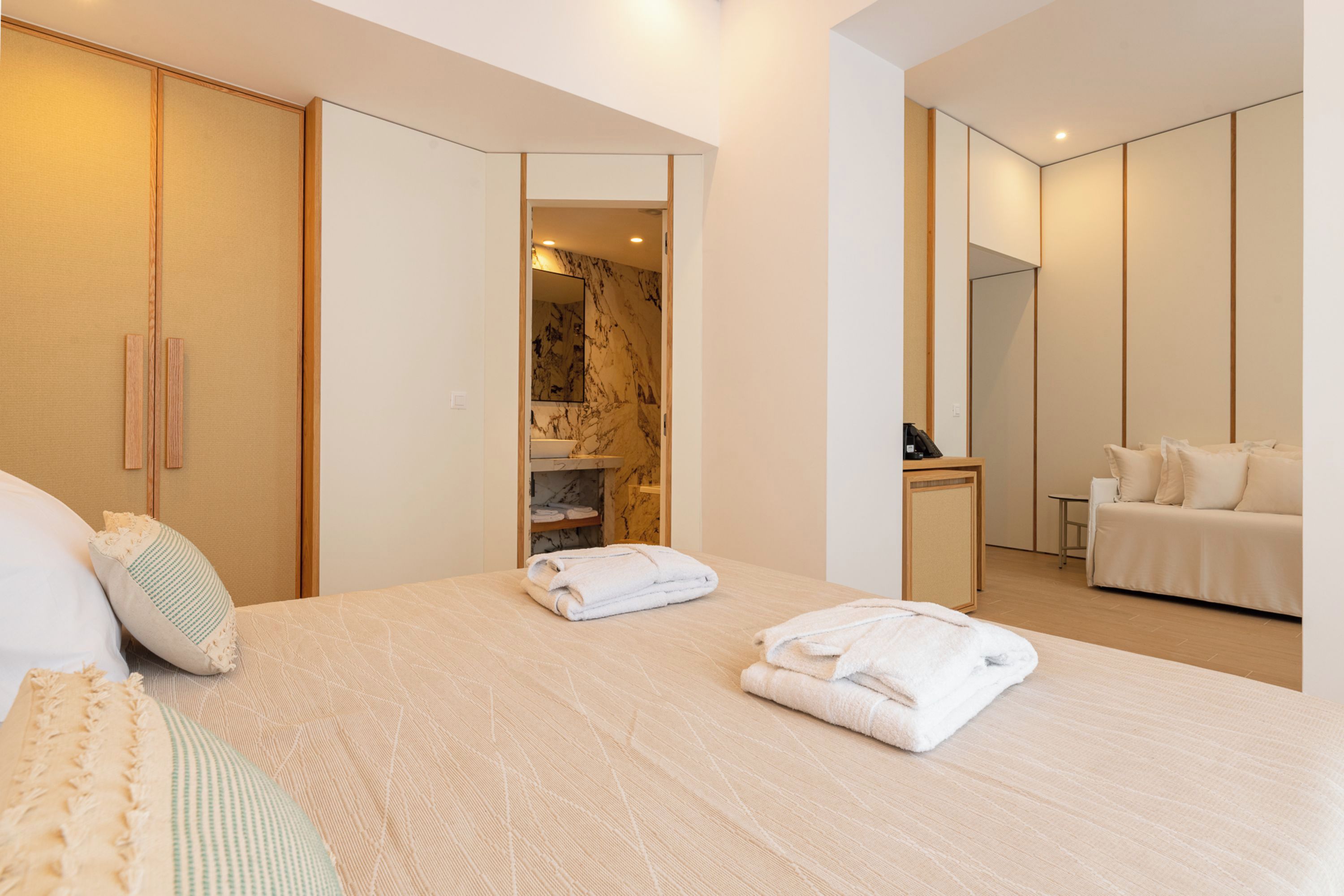 Ein modernes Hotelzimmer mit einem großen Bett, einer Sitzecke, einem Badezimmer und einem Kleiderschrank.