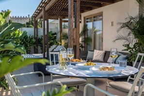 An outdoor dining area with a round table, chairs, and a bottle of wine. - The 12th City Hotel  (Rhodes)